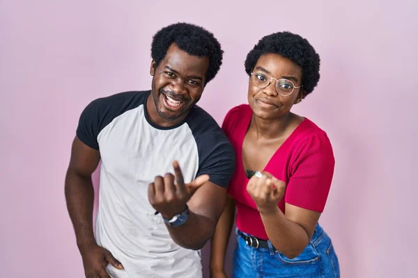 一对年轻的非洲裔美国夫妇站在粉红的背景上 招手欢迎快乐而微笑的来到这里 — 图库照片