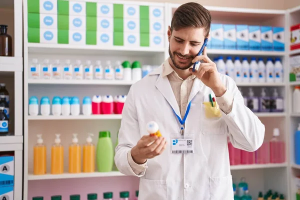 Young Caucasian Man Pharmacist Holding Pills Bottle Talking Smartphone Pharmacy — 스톡 사진