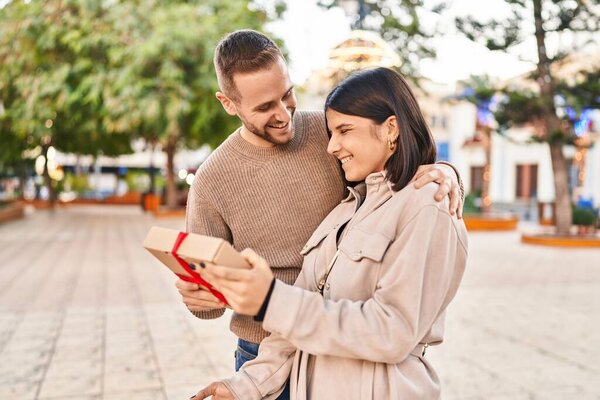 Man and woman couple smiling confident surprise with gift at park
