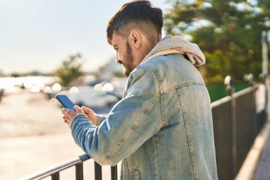 Sokakta akıllı telefon kullanan, kendine güvenen genç bir İspanyol.