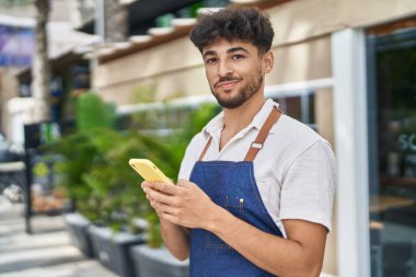 Young arab man waiter using smartphone working at restaurant
