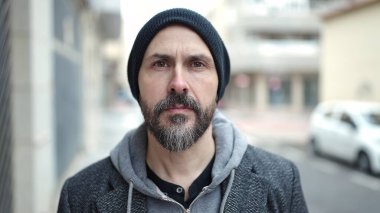 Sokakta ciddi bir ifadeyle duran genç kel adam.