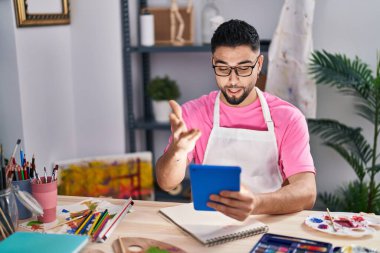Genç Arap ressam defterine resim çiziyor. Sanat stüdyosunda video görüşmesi yapıyor.