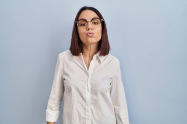 Young hispanic woman standing over white background looking at the camera blowing a kiss on air being lovely and sexy. love expression. 