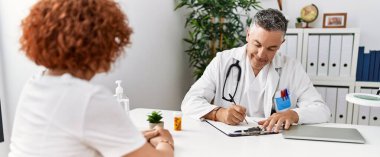 Doktor üniforması giyen orta yaşlı bir adam ve kadın klinikte tıbbi danışmanlık yapıyorlar.