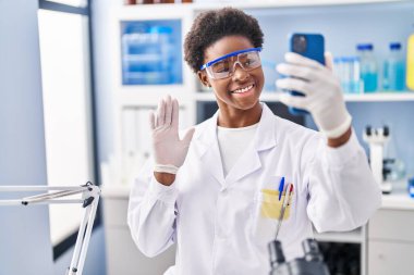 Afrika kökenli Amerikalı bir kadın bilim adamının laboratuarında çalışıyor. Akıllı telefonuyla video görüşmesi yapıyor. Pozitif ve mutlu görünüyor. 