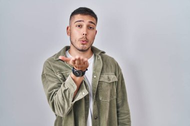 İspanyol asıllı genç bir adam izole edilmiş arka planda durup kameraya bakarak havada bir öpücük savuruyor ve sevimli ve seksi oluyor. aşk ifadesi. 