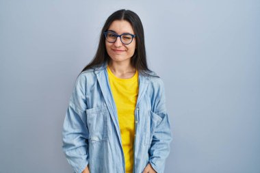 Mavi arka planda duran genç İspanyol kadın kameraya seksi bir ifadeyle bakıyor, neşeli ve mutlu bir yüzle.. 