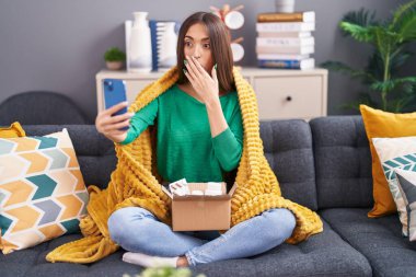 Genç, hasta, İspanyol bir kadın, doktorla video görüşmesi yapıyor. Ağzını eliyle kapatıyor, şok geçiriyor ve hata yapmaktan korkuyor. şaşırmış ifade 