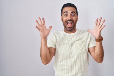 Tecrit edilmiş arka planda duran İspanyol sakallı adam çılgın ve başarıyı kollarını kaldırmış ve gözleri açık heyecanla haykırarak kutluyor. Kazanan konsept 