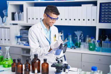 Afrikalı Amerikalı bilim adamı, laboratuardaki belgelere yazı yazıyor.