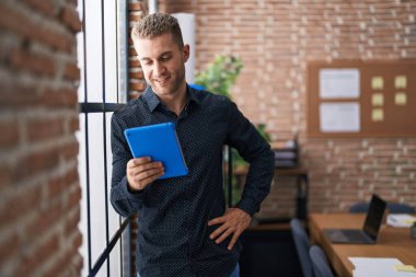 Young caucasian man business worker using touchpad leaning on window at office