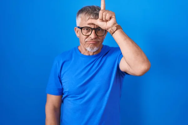 Homem Hispânico Com Cabelos Grisalhos Sobre Fundo Azul Zombando Pessoas — Fotografia de Stock