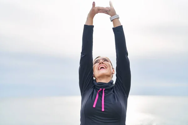 Young Hispanic Woman Wearing Sportswear Stretching Arms Seaside — Zdjęcie stockowe