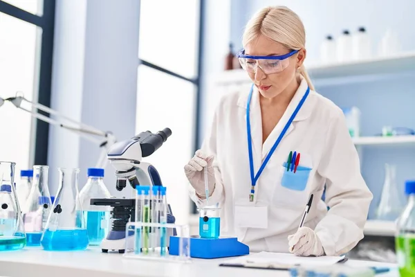 Mujer Rubia Joven Con Uniforme Científico Que Mide Líquido Laboratorio — Foto de Stock