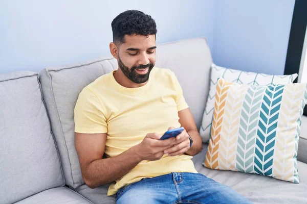 Young Arab Man Using Smartphone Sitting Sofa Home — Stok fotoğraf
