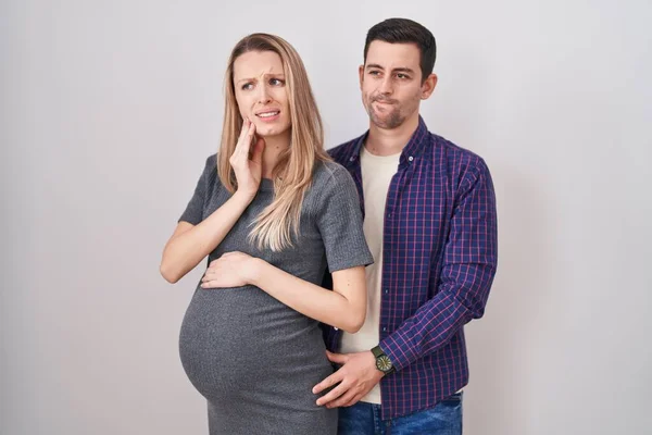 Casal Jovem Esperando Bebê Sobre Fundo Branco Tocando Boca Com — Fotografia de Stock