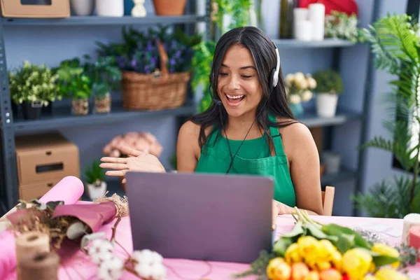 Brunette woman working at florist shop doing video call celebrating achievement with happy smile and winner expression with raised hand