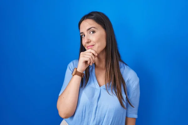 Jonge Brunette Vrouw Staat Blauwe Achtergrond Met Hand Kin Denken — Stockfoto