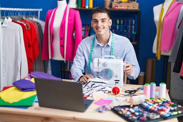 Young Hispanic Man Tailor Using Sewing Machine Laptop Sewing Studio — Stock fotografie