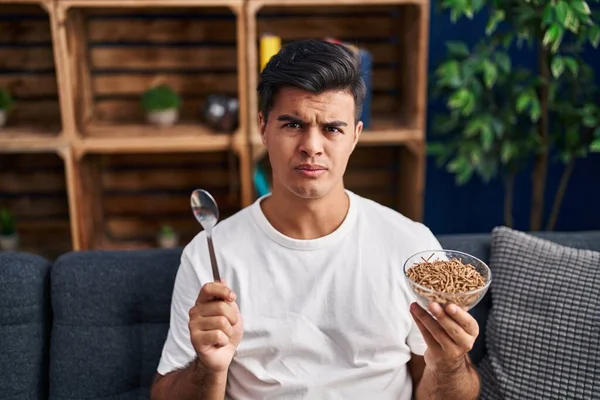 Hombre Hispano Comiendo Cereales Integrales Saludables Con Cuchara Escéptica Nerviosa — Foto de Stock
