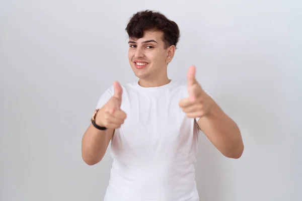 年轻的非二元男子穿着随意的白色T恤 手指指向相机 脸上带着快乐和滑稽的表情 充沛的精力和活力 — 图库照片