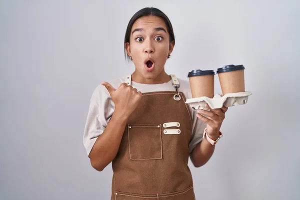 Mujer Hispana Joven Con Delantal Camarera Profesional Sosteniendo Café Sorprendido —  Fotos de Stock