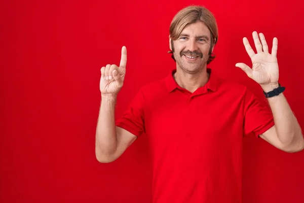 Caucasian man with mustache standing over red background showing and pointing up with fingers number six while smiling confident and happy.
