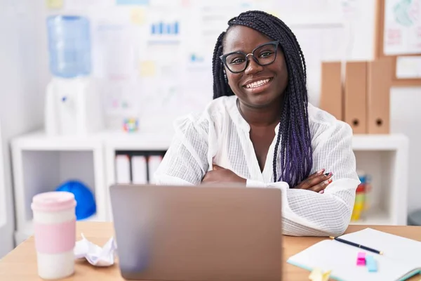 アフリカ系アメリカ人女性ビジネスワーカー笑顔自信を持って座ってとともに腕交差ジェスチャーでオフィス — ストック写真