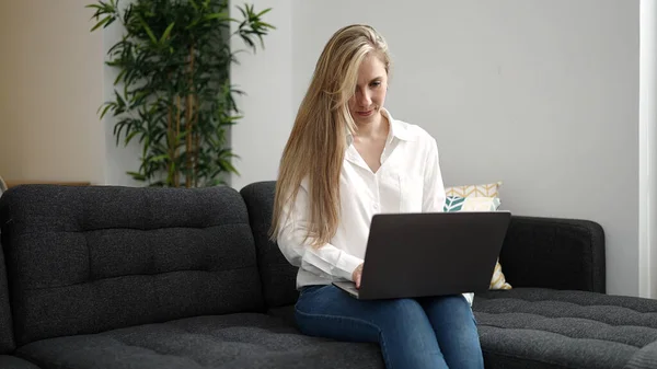 Młoda Blondynka Pomocą Laptopa Siedzi Kanapie Domu — Zdjęcie stockowe