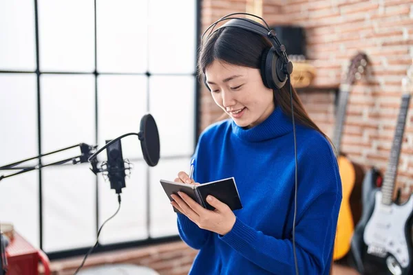 Chinese woman artist smiling confident composing song at music studio