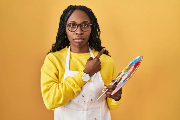 Mujer Africana Sosteniendo Paleta Pintores Señalando Con Dedo Mano Lado —  Fotos de Stock