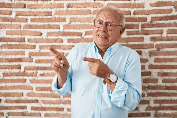 Starší Muž Šedivými Vlasy Stojící Přes Cihlovou Zeď Ukazuje Stranou — Stock fotografie