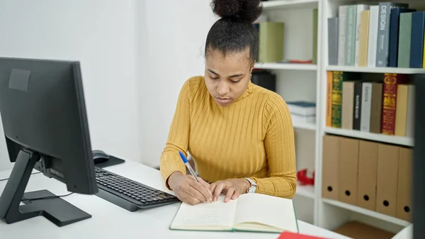 図書館でノートを取るコンピュータを使用して若いアフリカ系アメリカ人女性の学生 — ストック写真