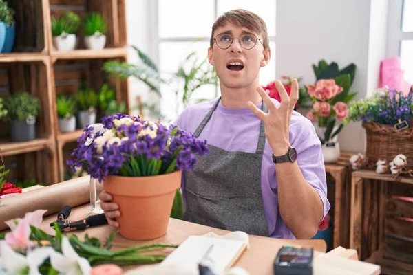 花屋で働く白人ブロンドの男は狂気と怒鳴り 積極的な表情と腕を上げて叫びました フラストレーションコンセプト — ストック写真