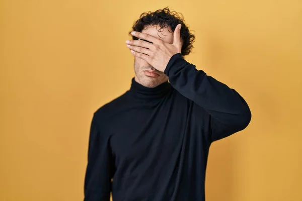 stock image Hispanic man standing over yellow background covering eyes with hand, looking serious and sad. sightless, hiding and rejection concept 