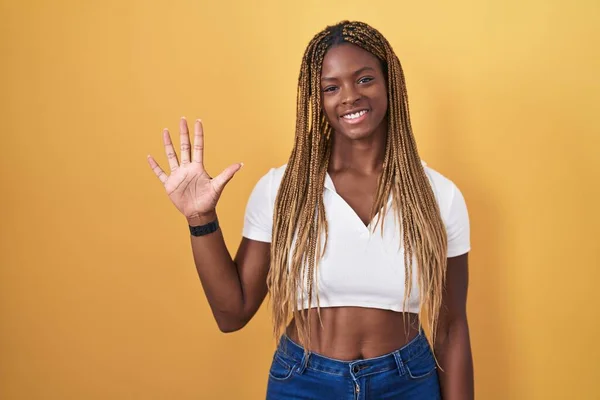 Африканская Американка Плетеными Волосами Стоящая Желтом Фоне Показывающая Пальцами Номер — стоковое фото