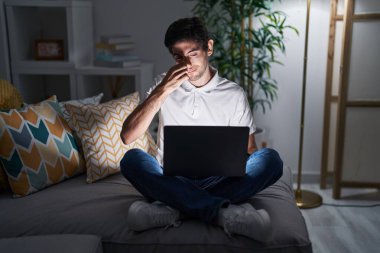 Genç İspanyol adam gece evde dizüstü bilgisayar kullanıyor. Kokuşmuş, iğrenç, dayanılmaz bir koku alıyor. Parmakları burnunda nefesini tutuyor. Kötü kokuyor. 