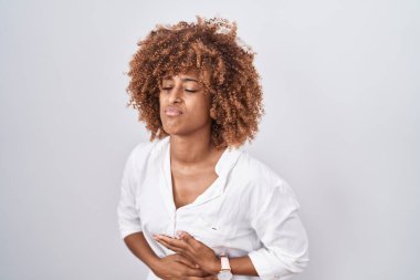 Beyaz arka planda duran kıvırcık saçlı, hazımsızlık, acı verici bir hastalık yüzünden midesi üstünde duran İspanyol bir kadın. Ağrı kavramı. 