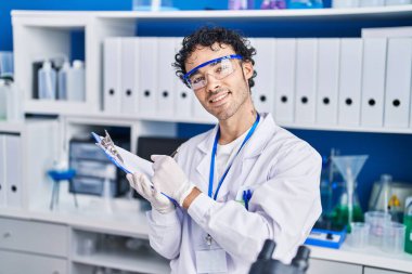 Latin asıllı genç bilim adamı laboratuardaki belgeye yazı yazıyor.