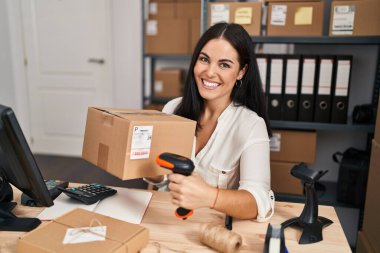 Genç ve güzel İspanyol kadın ecommerce iş adamı ofiste tarama paketi