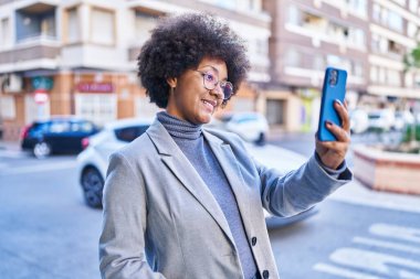Afrikalı Amerikalı kadın yöneticiler sokakta akıllı telefonla selfie çekiyorlar.