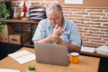 Middle age grey-haired man business worker suffering for wrist pain working at office