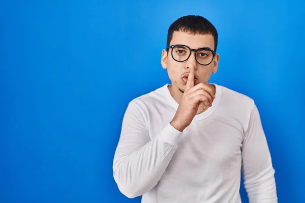年轻的阿拉伯男子穿着随意的白色衬衫和眼镜 要求保持安静 手指放在嘴唇上 沉默和秘密概念 — 图库照片