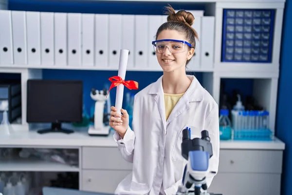 Teenager Girl Working Scientist Laboratory Holding Degree Looking Positive Happy — Stock Photo, Image