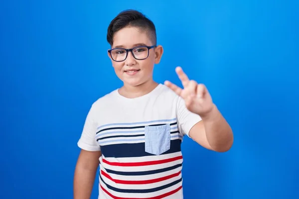 Mladý Hispánec Stojící Nad Modrým Pozadím Usmívající Kameru Ukazující Prsty — Stock fotografie