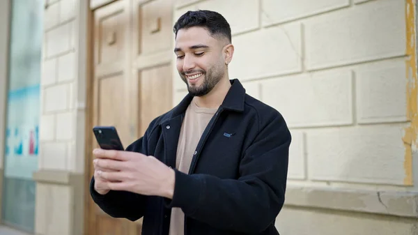 若いアラブ人男笑顔自信を持って使用してスマートフォンでストリート — ストック写真