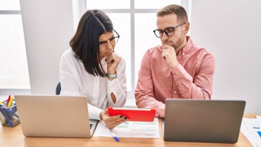 Ofiste çalışan erkek ve kadın işçiler dizüstü bilgisayar ve dokunmatik ped kullanıyorlar.