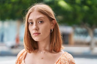 Sokakta duran rahat yüzlü, genç kızıl saçlı kadın.