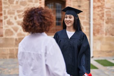 İki kadın anne ve kız kampüs üniversitesinde mezuniyeti kutluyorlar.